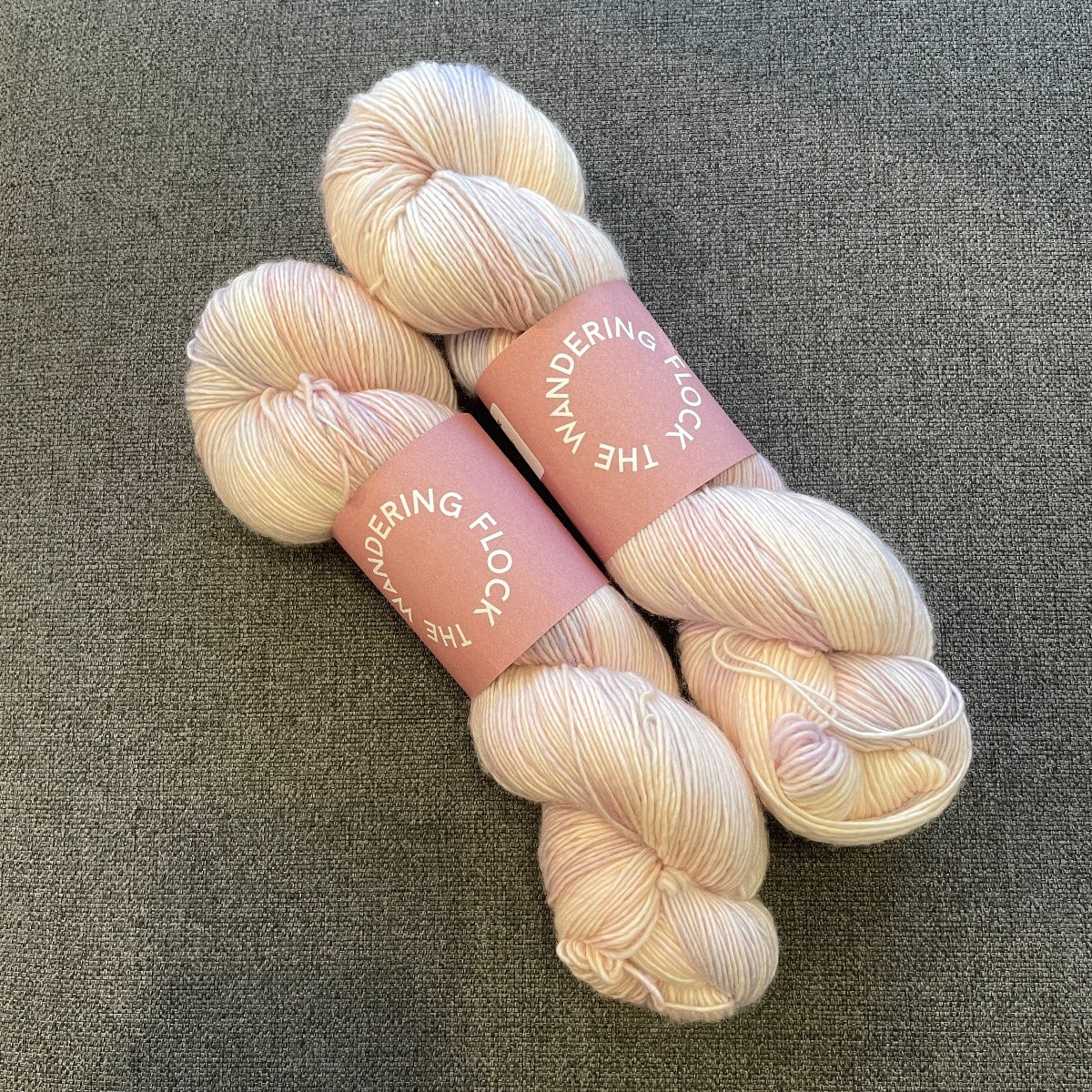 Skein of yarn in pale pinks with a hint of purple on a grey background. 