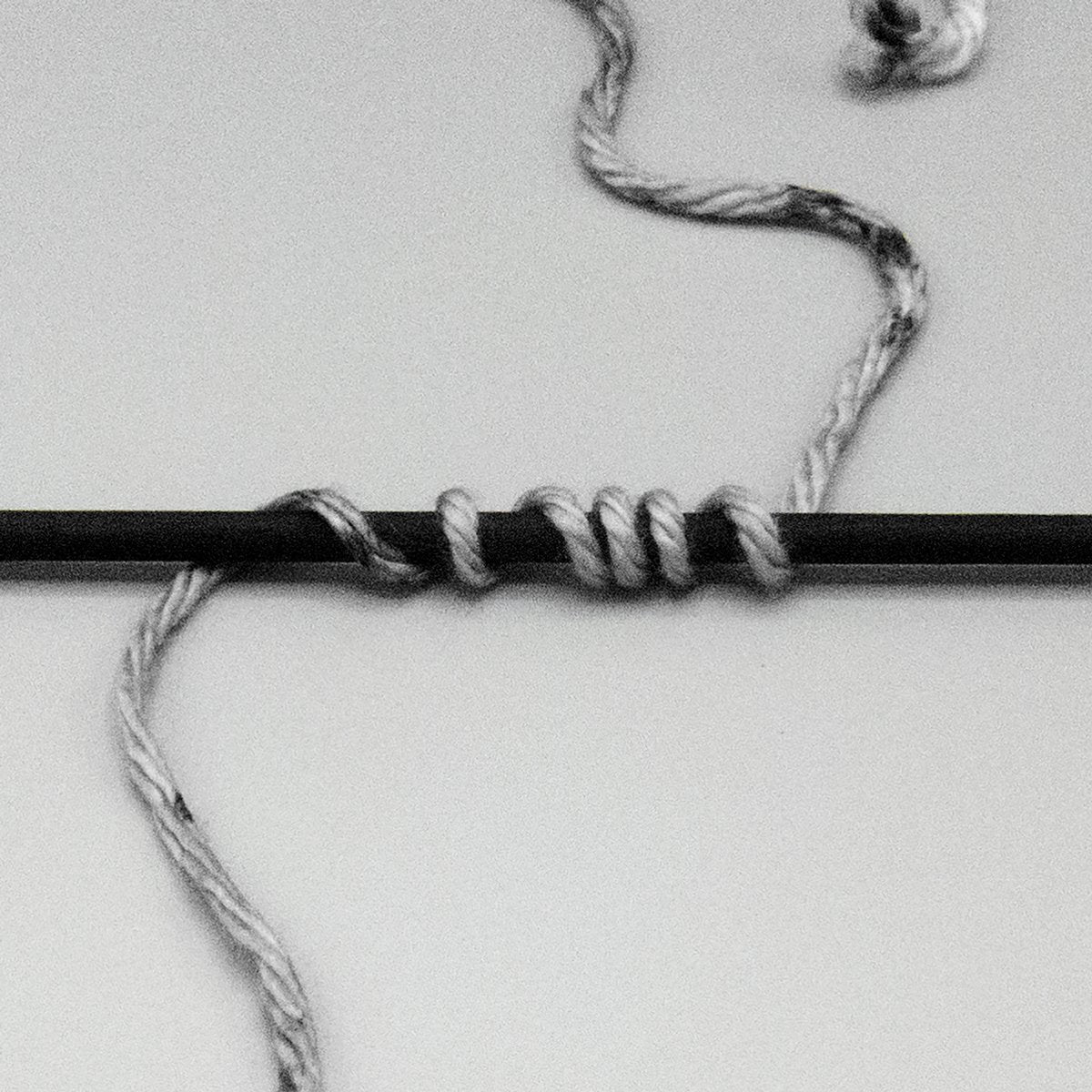 Grey bulky yarn wrapped around a black stick.