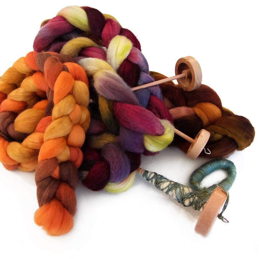Multi colored hand dyed fiber and wooden drop spindles. 