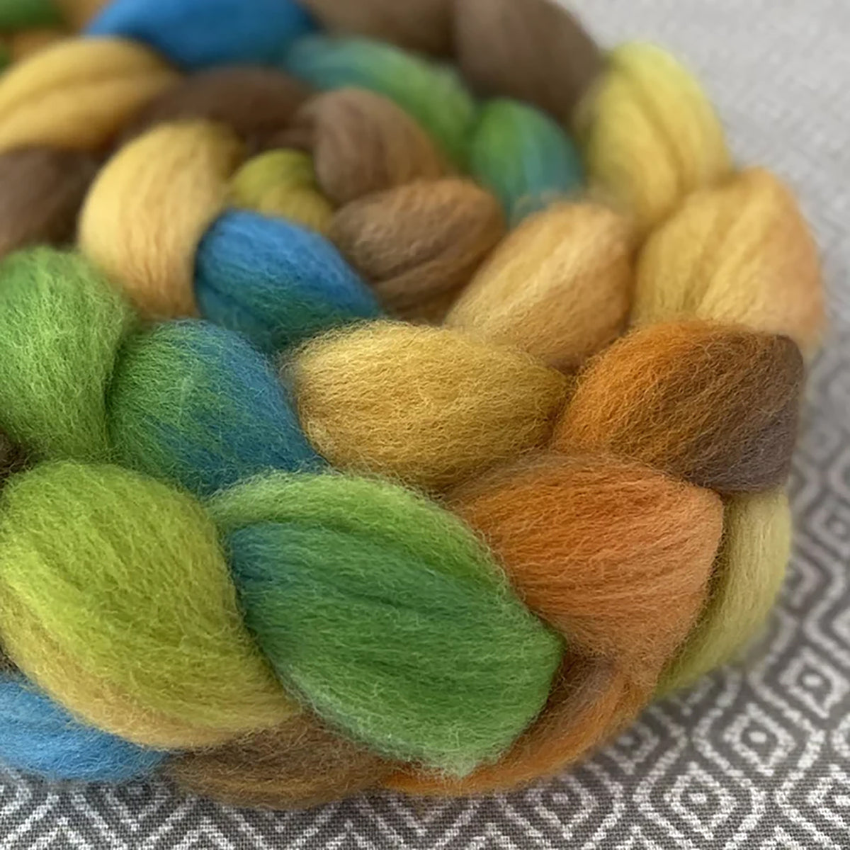 Detail of Greenwood Fiberworks Pigtails 1972 in colors sandy yellow, rust orange, teal, brown, and green