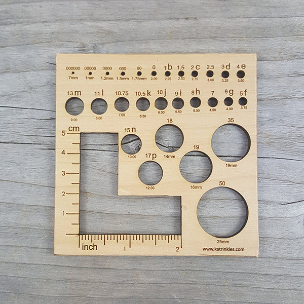 A gauge tool with knitting needle gauge and a 2”x2” swatch gauge 
