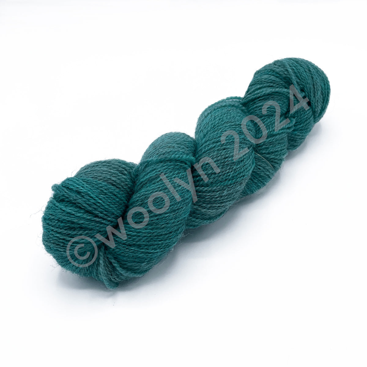 A skein of Woolerton Estates Farmhand Beatrix, a vibrant light teal color with deep grey undertones.
