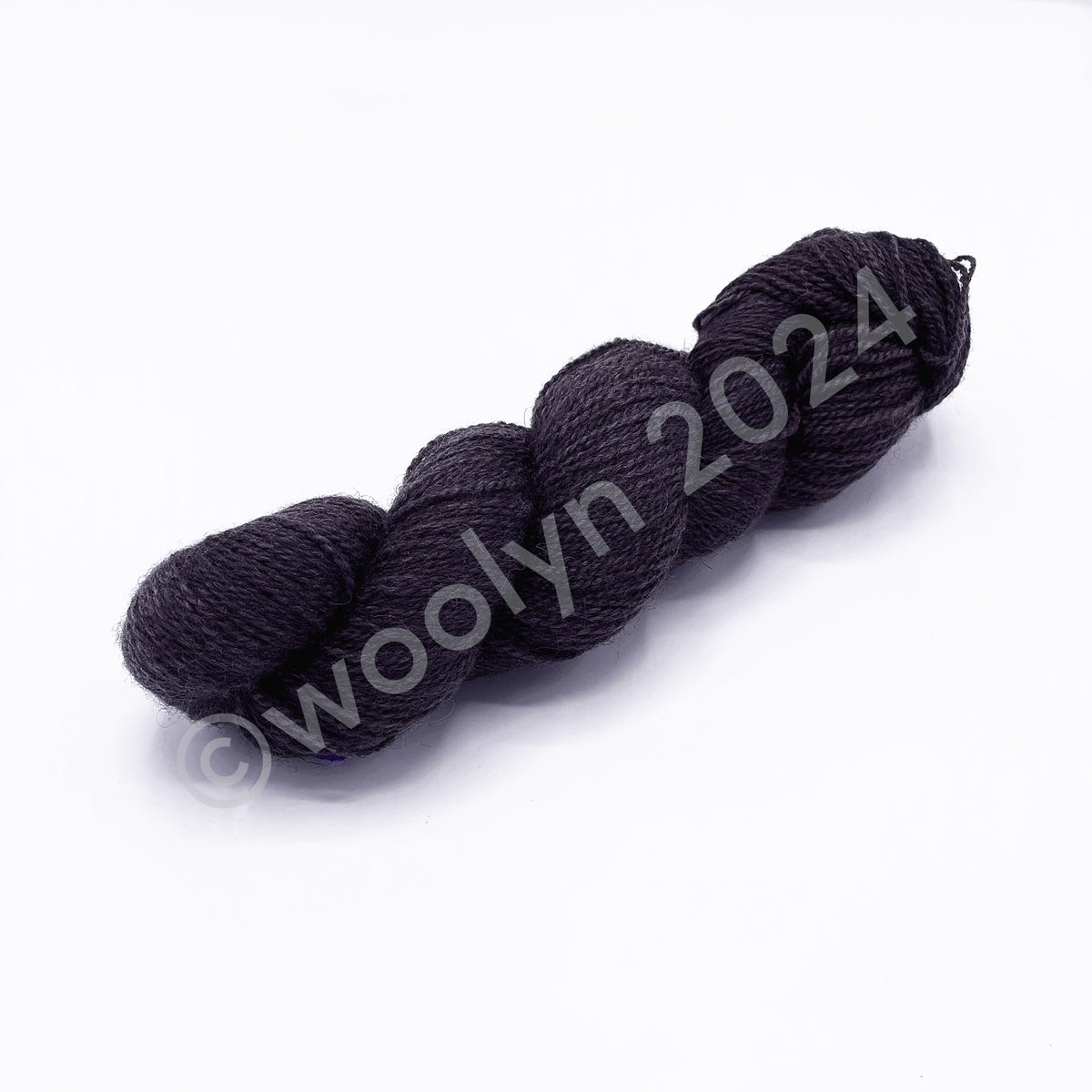 A skein of Woolerton Estates Farmhand Damian, a dark greyish mauve color.