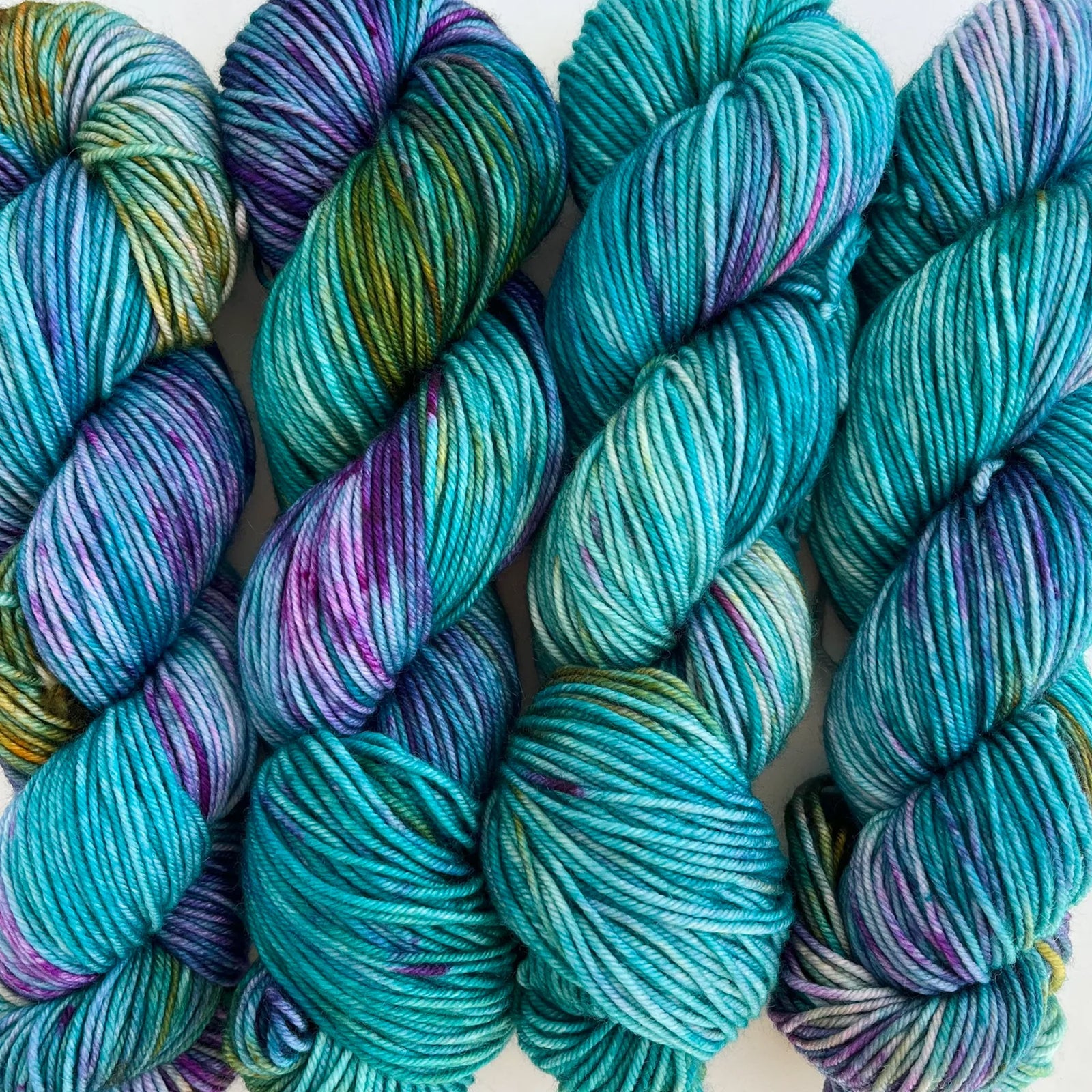 Skeins of Tributary Worsted Knitopia,  variegated teal, purple, and green 
