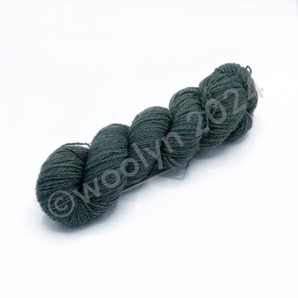 A skein of Woolerton Estates Farmhand Rita, a soft light green with grey undertones.