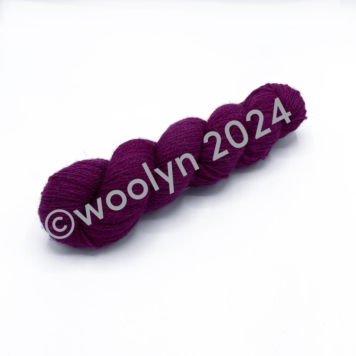 A skein of Woolerton Estates Farmhand Rufus, a bold magenta pink color with grey undertones.