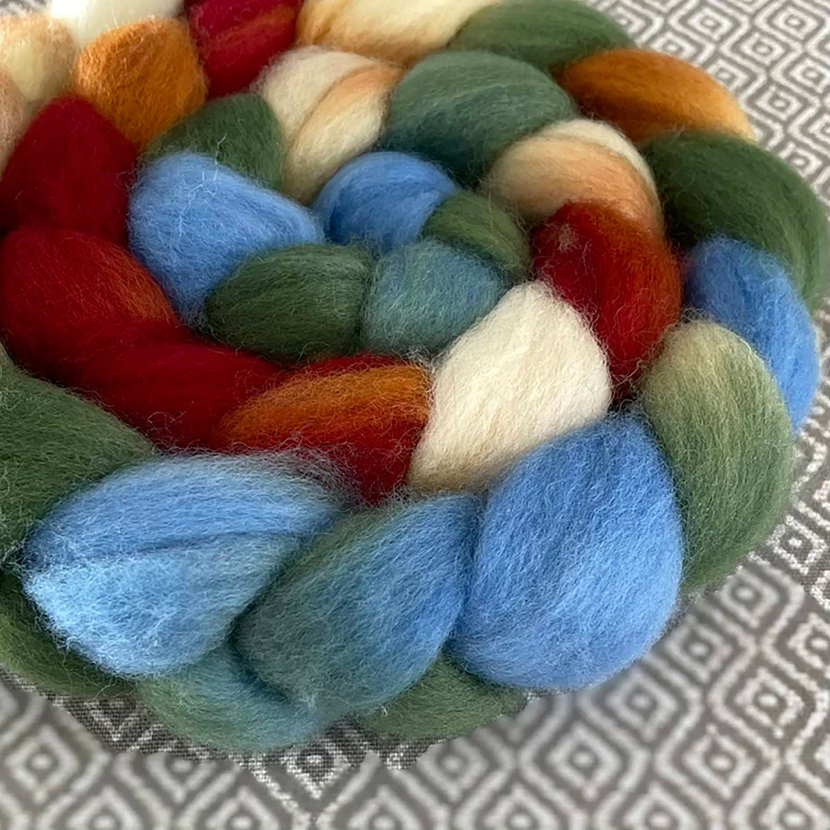 Detail of Greenwood Fiberworks Pigtails School House Rock in colors rust, light blue, green, and cream white 