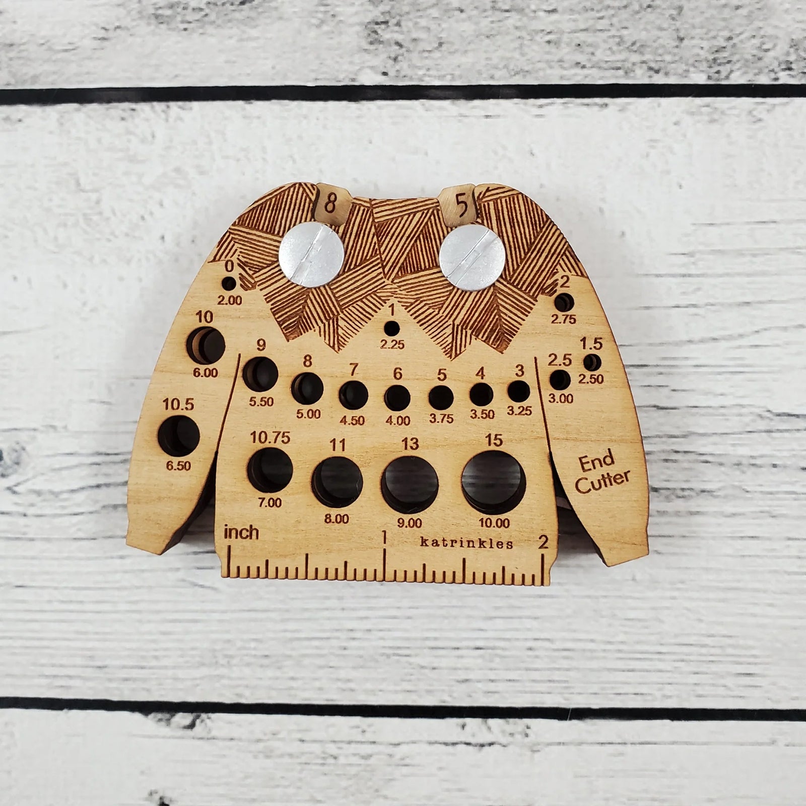 Sweater shaped wooden multi tool which includes: needle gauge, 2 inch ruler edge, row counter, and yarn end cutter