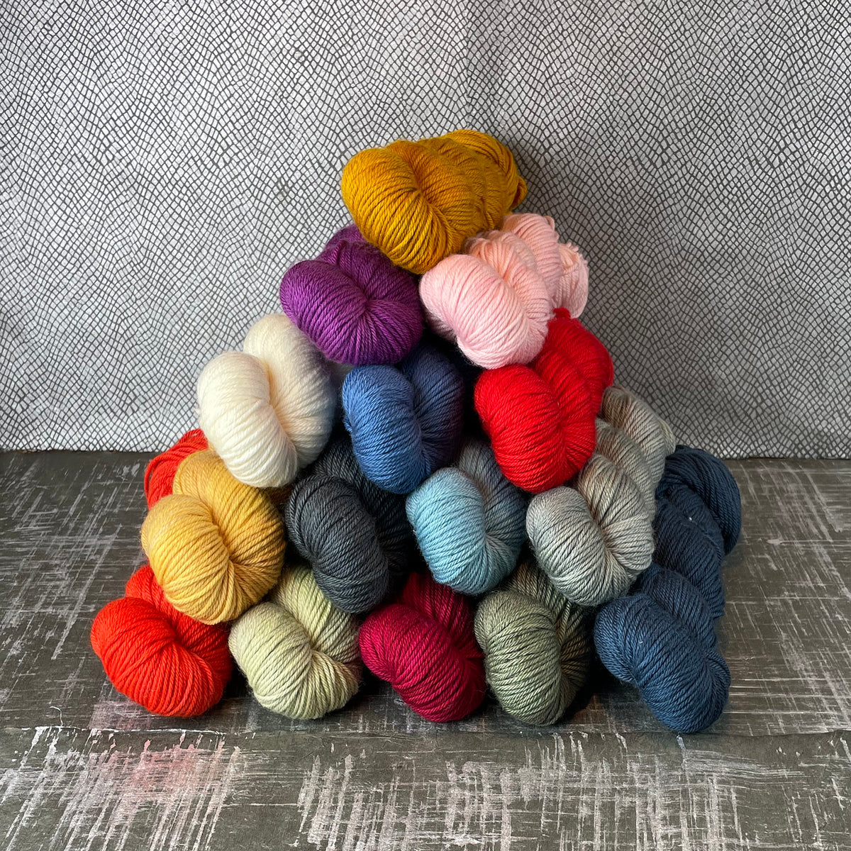 Skeins of Tesserae Kissa in different colors stacked in a pyramid shape