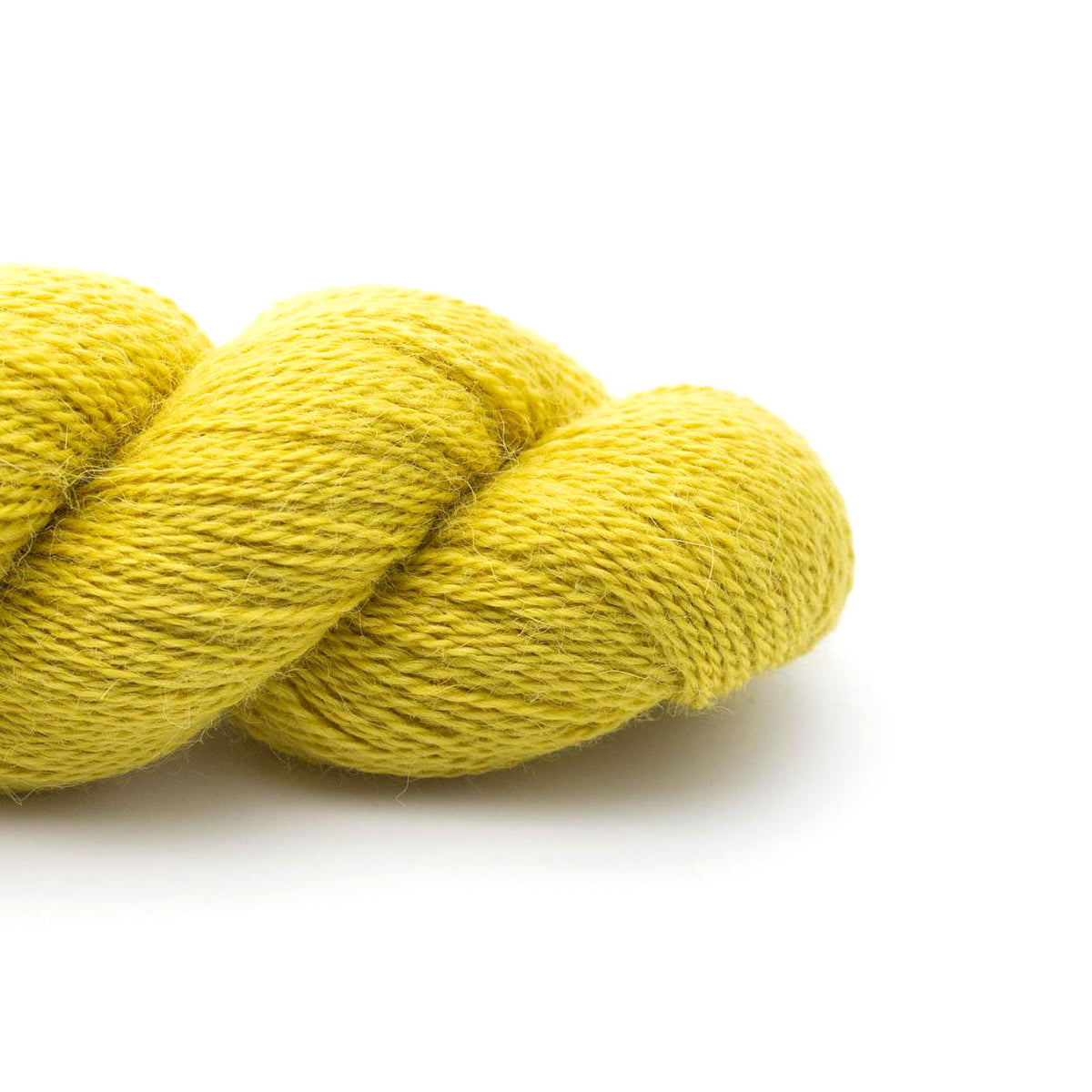 A skein of Kremke Baby Alpaca Apple in a bright greenish yellow