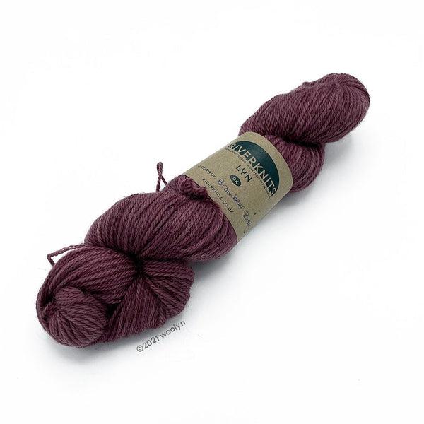 A skein of River Knits Lyn  a worsted plied DK weight yarn in Brombeer Zweig a dusty rose color.