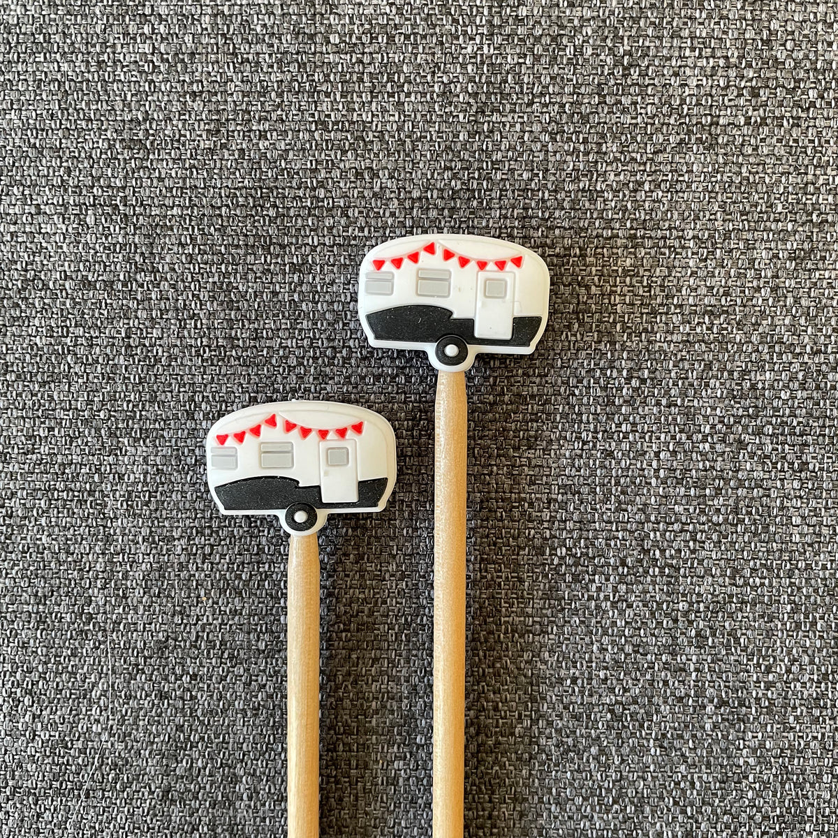 Two knitting needles topped with camper stitch stoppers arranged in