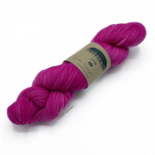 A skein of River Knits Lyn a worsted plied DK weight yarn in Cosmos a bright pink color.