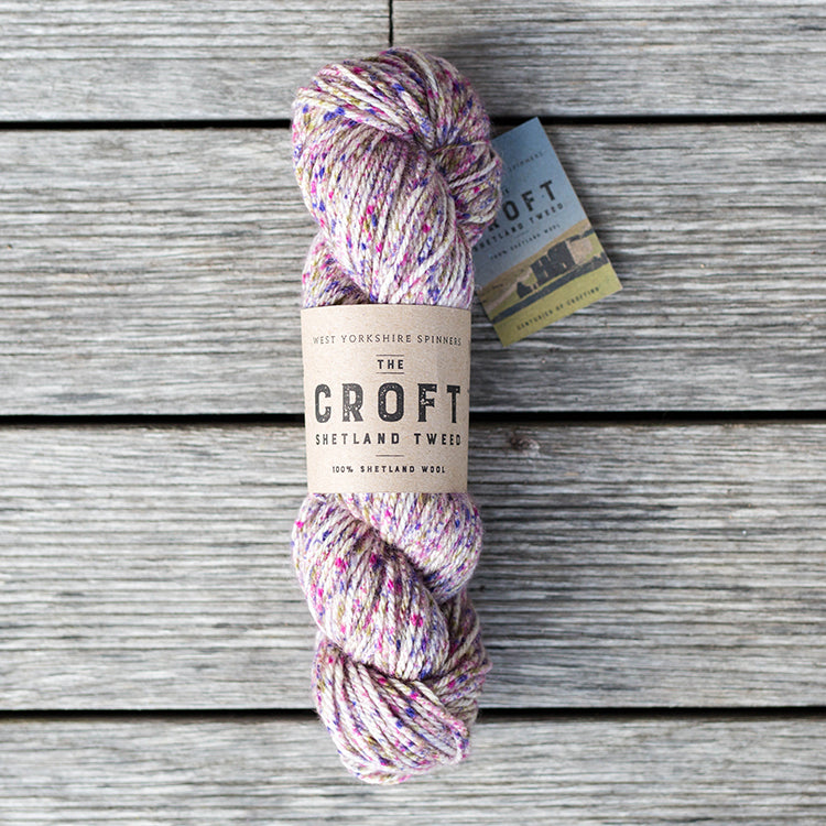 West Yorkshire Spinners the Croft Shetland Tweed in Heylor a white base yarn with purple, olive and magenta speckle.