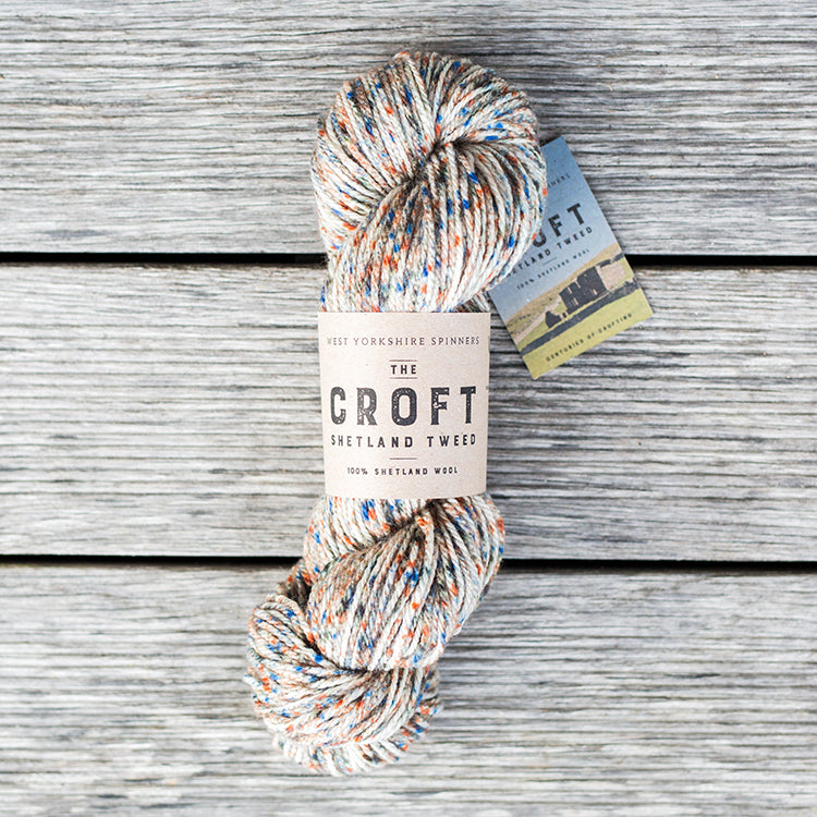 West Yorkshire Spinners the Croft Shetland Tweed in Stonybreck a white base yarn with orange, grey and royalblue speckle.