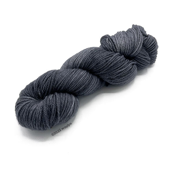 A skein of Knitted Wit Worsted Superwash in a solid dark grey color. 