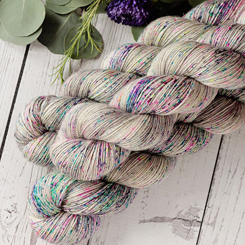 Yarn Love Amy March in Material Girl a white based yarn with neon multi-colored speckles.