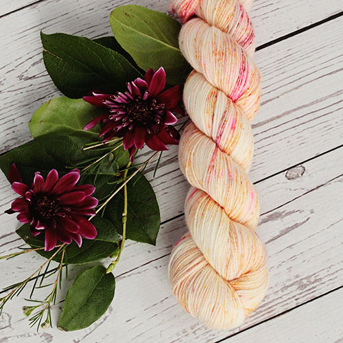 Yarn Love Amy March in Misty Sunrise a cream based yarn with yellow undertones and pink, brown and orange speckles.