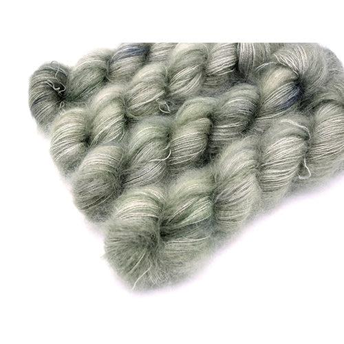 Skeins of Murky Depths Mirage Stone Cold, a gently variegated yarn in shades of light yellow grey. 