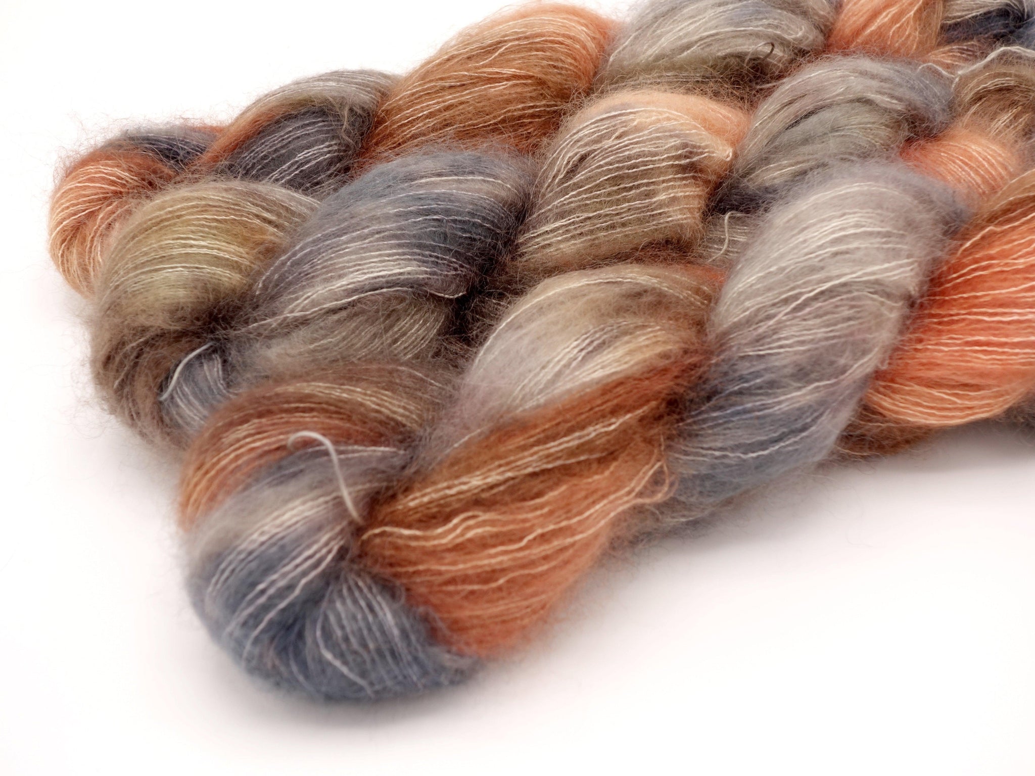 Skeins of Murky Depths Mirage The Dreamtime, a variegated yarn in tones of pale orange, brighter orange and browns with purply blue greys. 