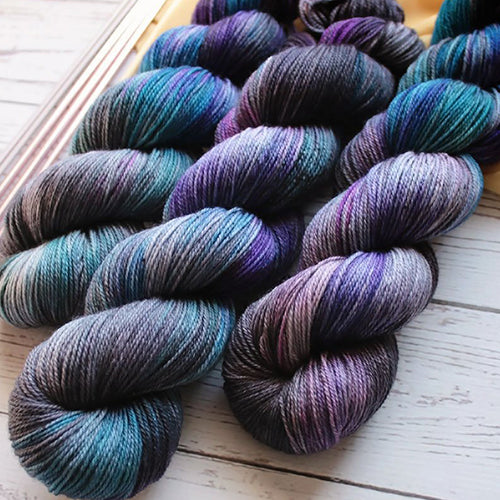 Yarn Love Juliet Oil Slick a variegated yarn in turquoise, royal blue, purple and dark grey.