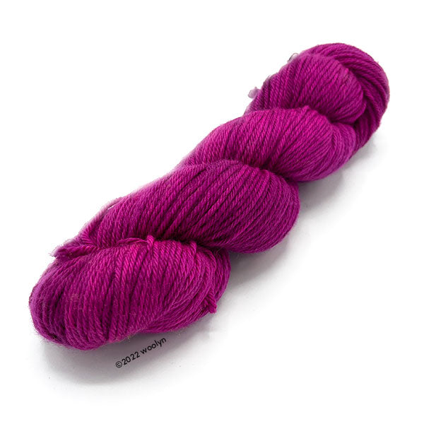 A skein of Knitted Wit Worsted Superwash in Sexy Lovin Eyes a medium magenta color.