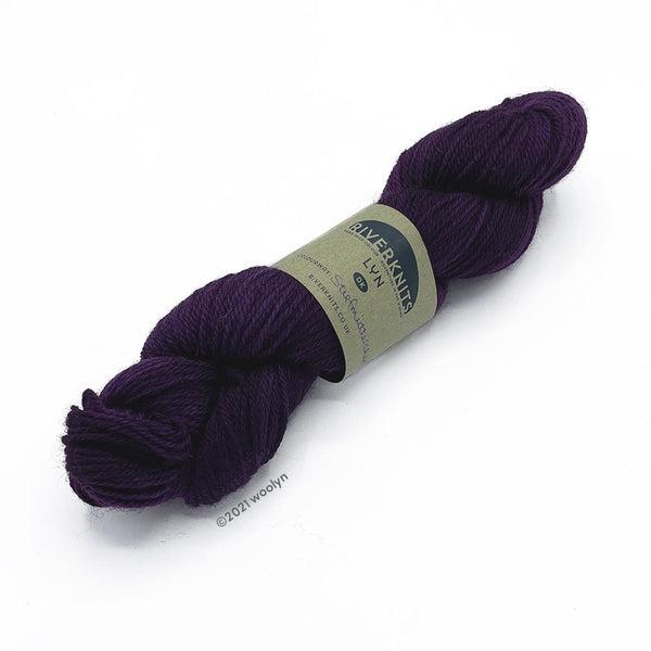 A skein of River Knits Lyn a worsted plied DK weight yarn in Stiefmutterchen, a deep purple color.