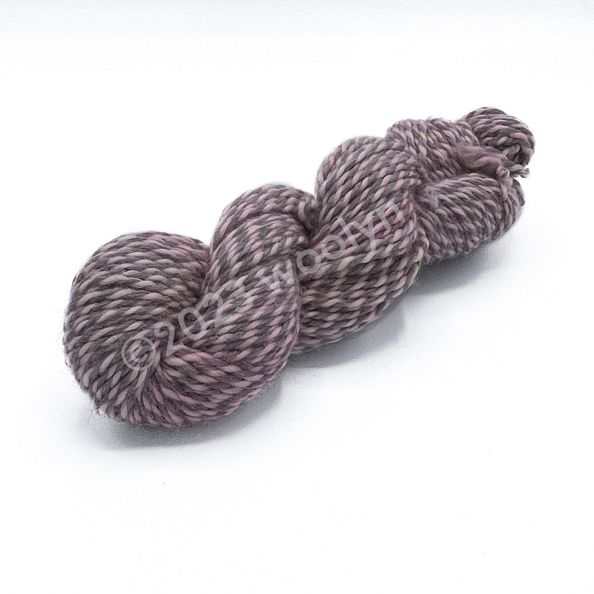 A skein of Tesserae Chonky in Toe Beans, a light pink plied with a light grey