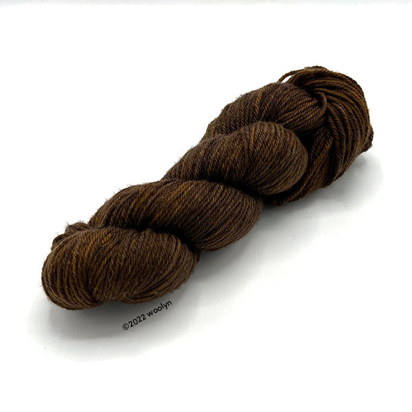 A skein of Knitted Wit Worsted Superwash in Tree Bark a dark brown color.