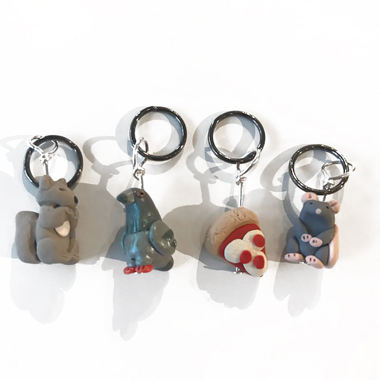 Shop exclusive Woolyn Wee Ones Stitch Markers. The set includes 4 stitch markers: squirrel, pigeon, pizza and a rat. 