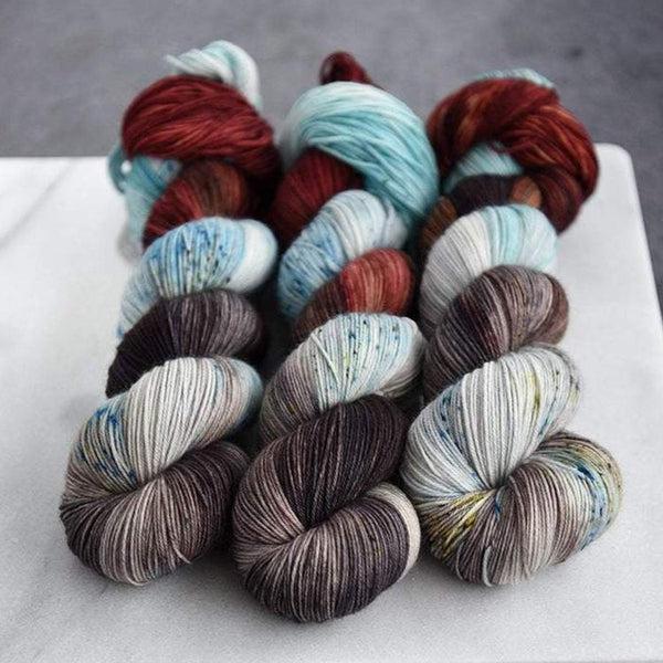 Skeins of Destination Yarn Souvenir Brooklyn, a variegated yarn in speckled cream and pale blue with tonal warm medium brown and dark cool brown.  