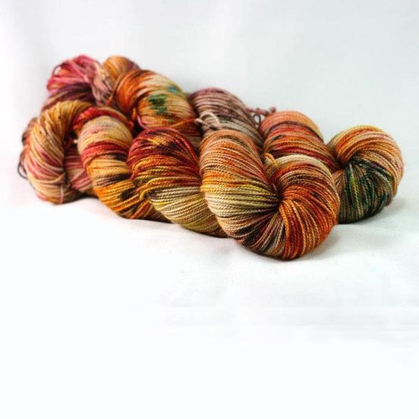 Skeins of Destination Yarn Souvenir Fall Run, a bright variegated yarn with shades of yellow, orange, red, beige and dark green.