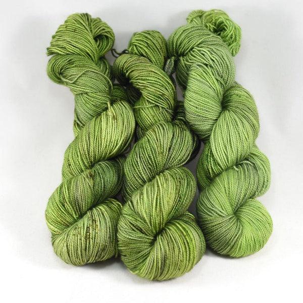 Skeins of Destination Yarn Souvenir Scottish Highlands, a bright tonal spring green with darker green speckles.