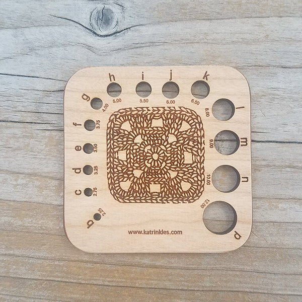 Wooden needle/Hook Gauge with a granny square on it. Measures approximately 3" x 3".