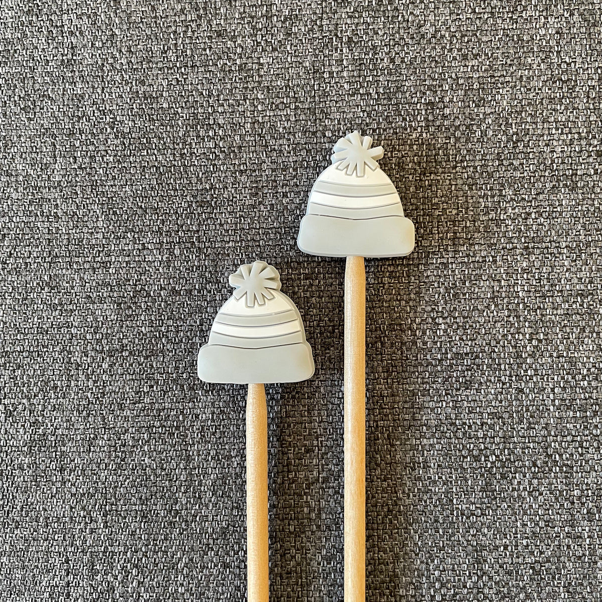Two knitting needles topped with grey hat Stitch Stoppers