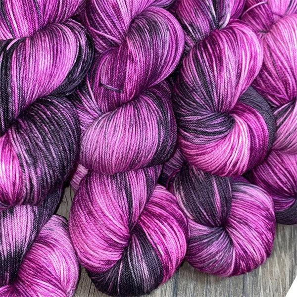 Skeins of JEMS Monster Minis Ambrosia, a variegated yarn in bright pink purple with dark purple.