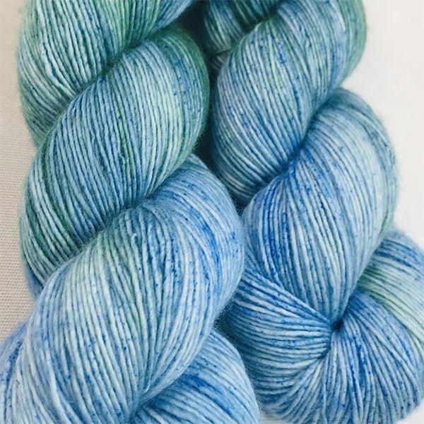 Skeins of JEMS Monster Minis Charybdis, a gently variegate tonal yarn in light blues and turquoise with some darker speckling.