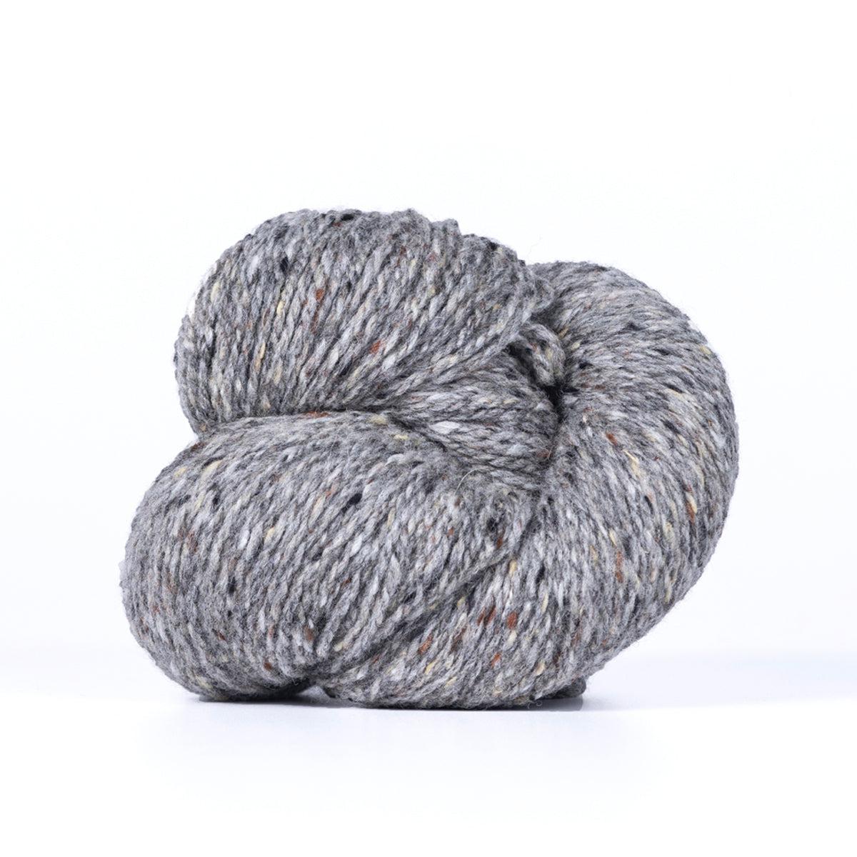 A skein of Kelbourne Woolens Lucky Tweed Med. Grey, a medium grey with lighter and darker grey flecks.