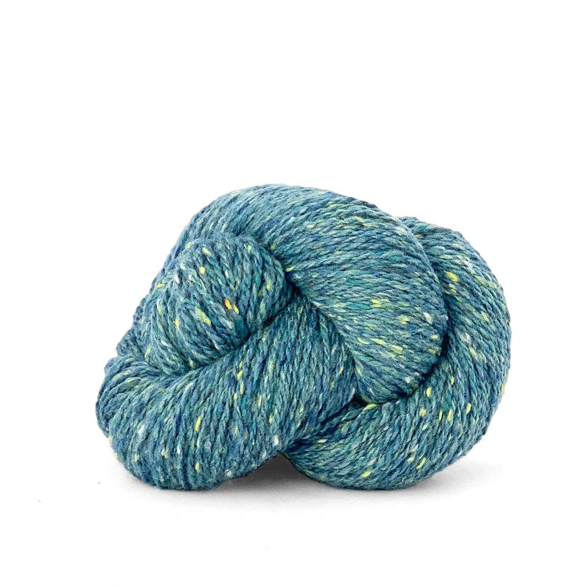 A skein of Kelbourne Woolens Lucky Tweed Seaglass, a light blue green with yellow and darker blue flecks. 