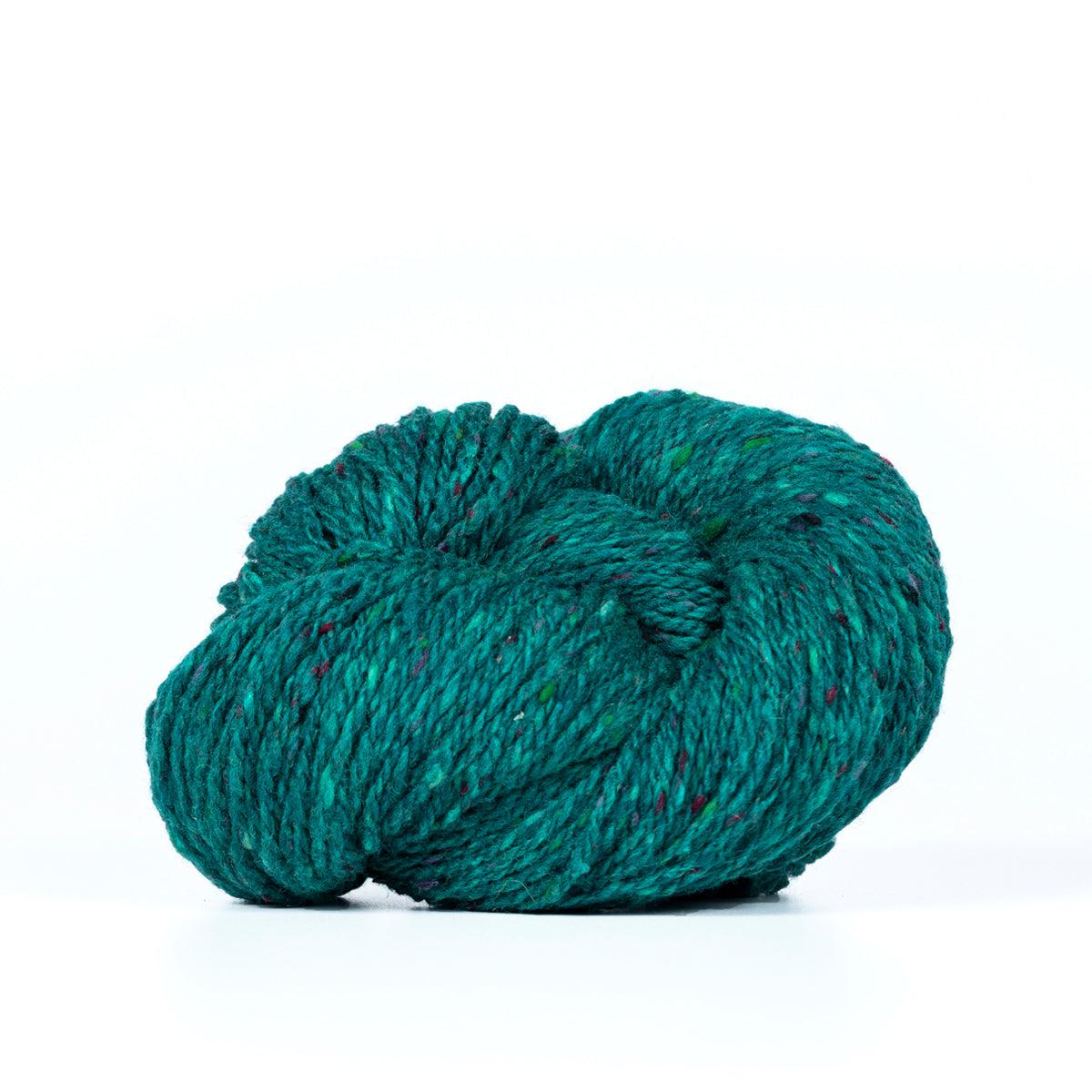A skein of Kelbourne Woolens Lucky Tweed Veridian, a bright  teal with lighter and darker blue and green flecks.