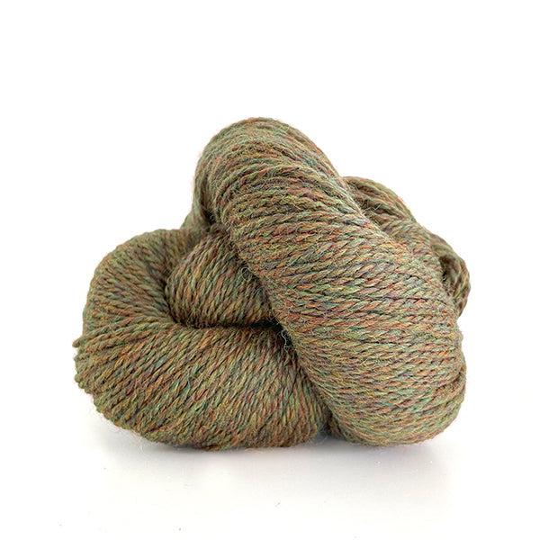 A skein of Kelbourne Woolens Scout Autumn Heather 703, a heathered yellowy green brown with orange.