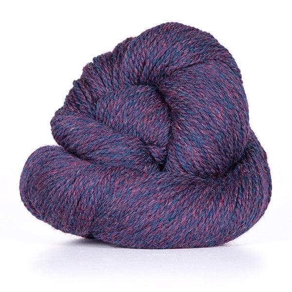 A skein of Kelbourne Woolens Scout Plum Heather 501, a heathered dark blue and orchid yarn.