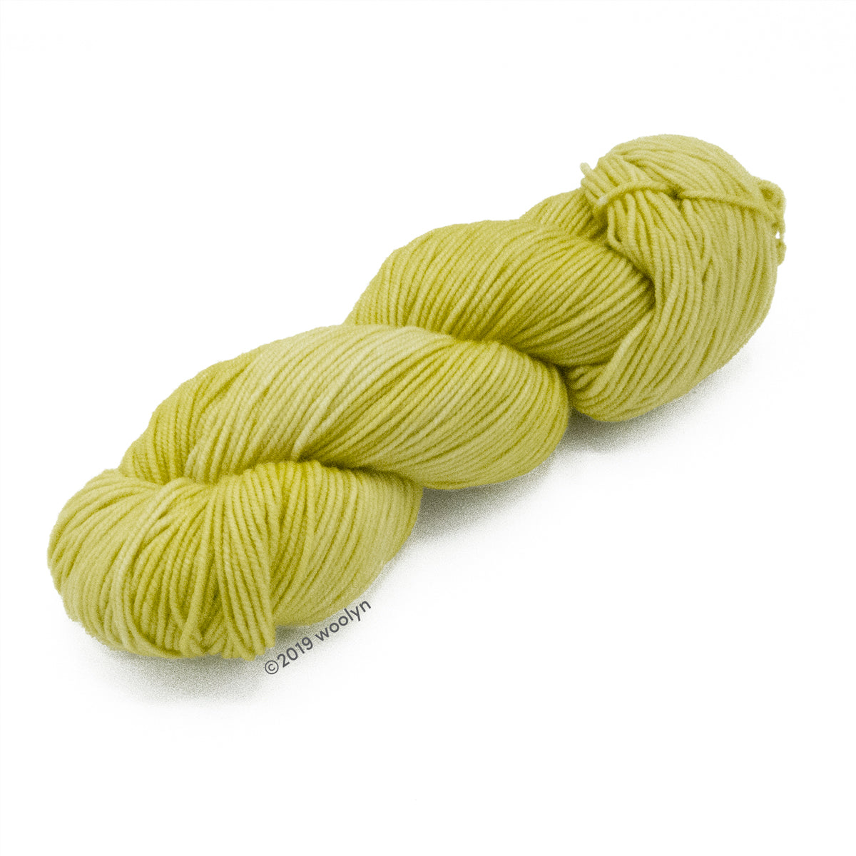 A skein of Knitted Wit Victory DK in Celery Hearts a pale yellow green color.