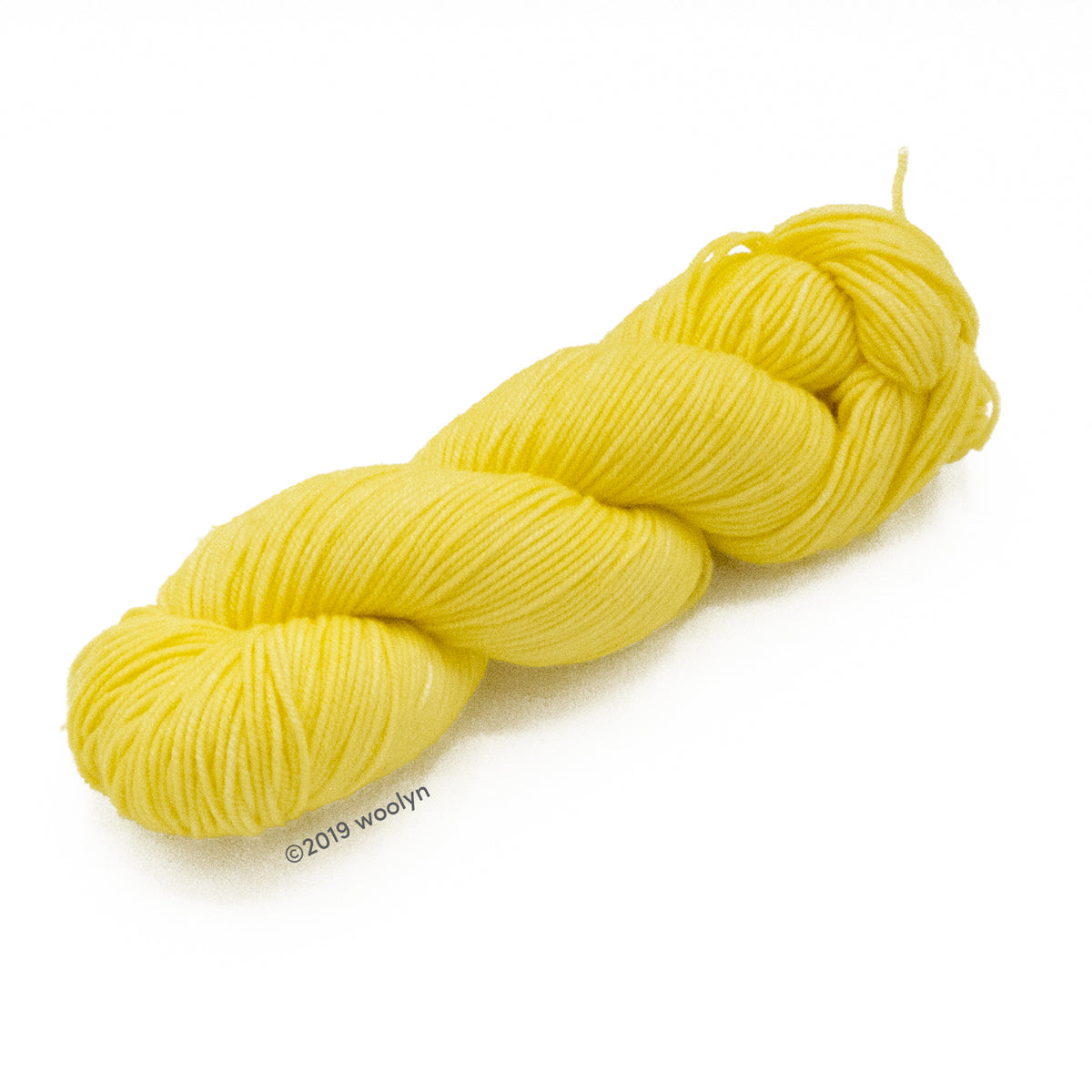 A skein of Knitted Wit Victory DK in Genteel a solid pale yellow color.