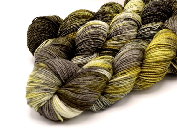 Skeins of Murky Depths Deep Sock Knight in Tarnished Armor, a variegated yarn in shades of cream, dark brown and brassy dark yellow.