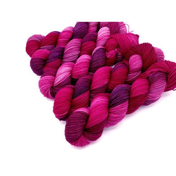 Skeins of Murky Depths Deep Sock Tell Tale Heart, a variegated yarn in shades of bright pink, fuchsia and rosy purple. 