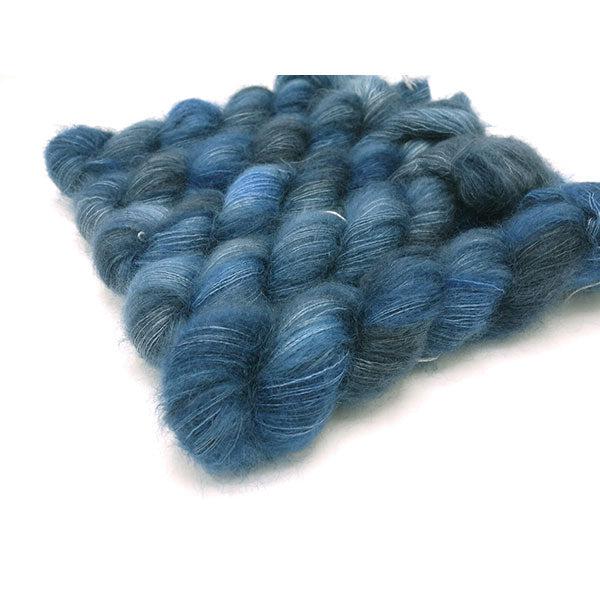 Skeins of Murky Depths Mirage For Beatrice, a variegated yarn in shades of bright and dark blue and dark grey.