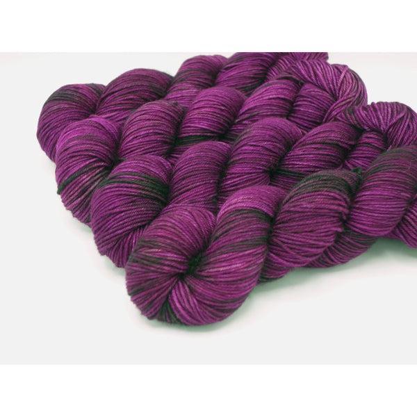 Skeins of Murky Depths Neptune DK Girl Gone Made, a variegated yarn with mostly reddish purple and bits of dark brownish grey and lighter purple.