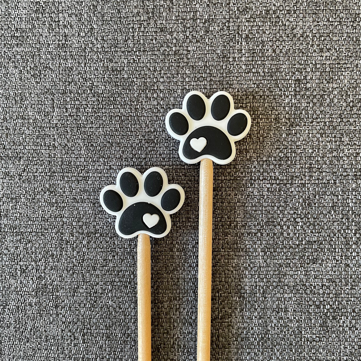 Two knitting needles topped with black paw print Stitch Stoppers