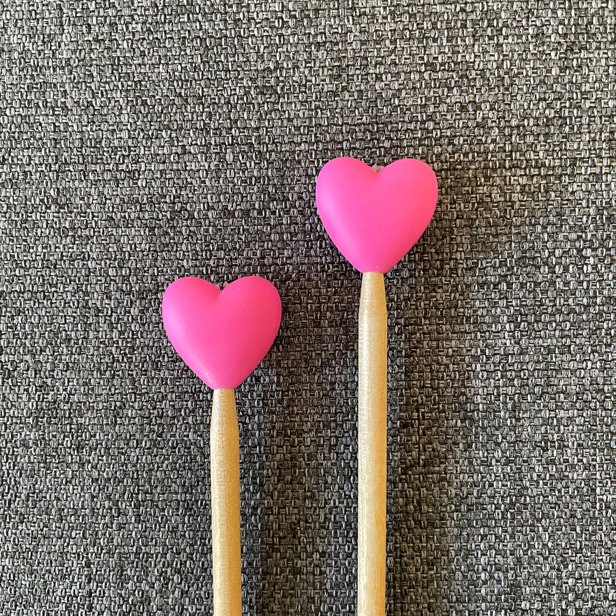 Two knitting needles topped with pink heart Stitch Stoppers